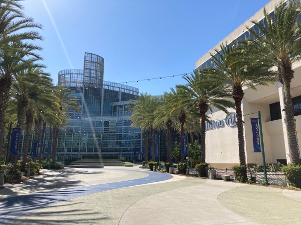 View of the grand plaza walkway, lined with palm trees, leading past the Hilton Anaheim hotel to the Anaheim Convention Center.