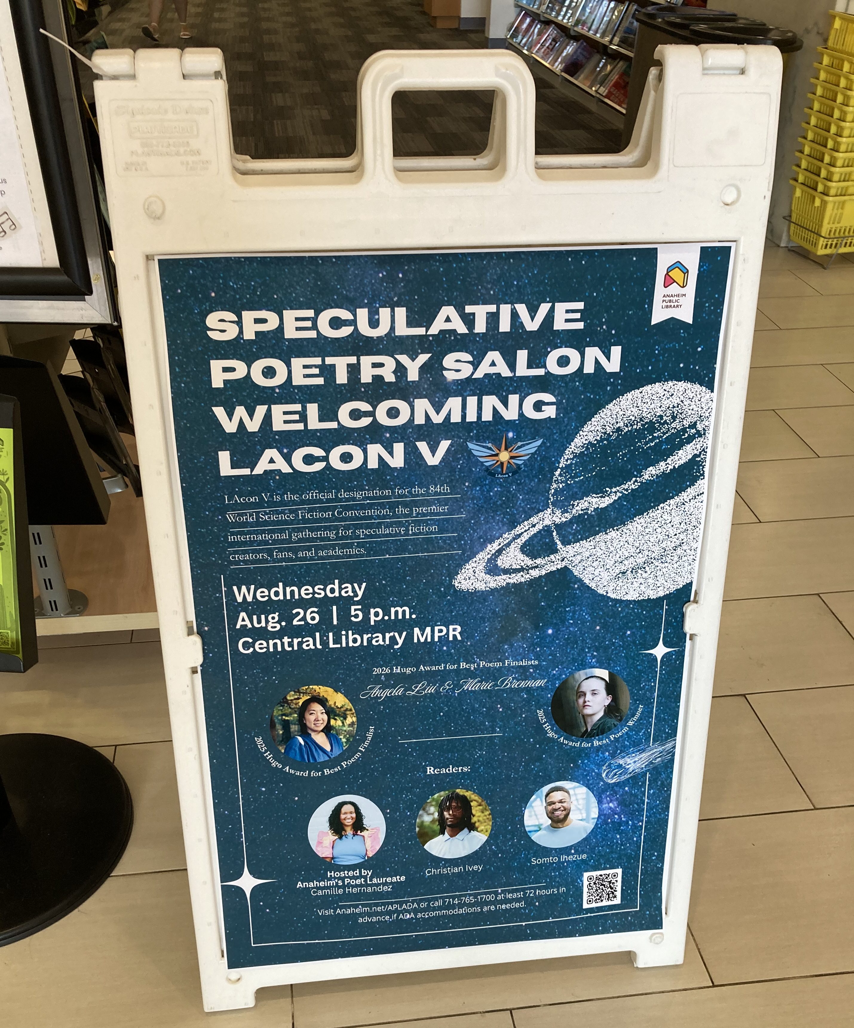 Sandwich board in the Anaheim Central Library with a blue and white planetary background, advertising the Speculative Poetry Salon Welcoming LAcon V.